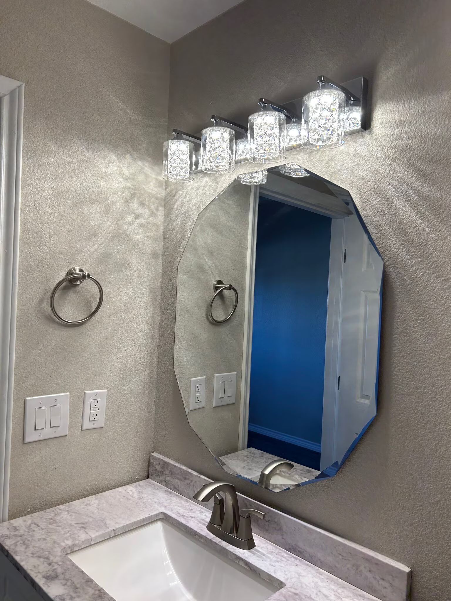A bathroom with a sink , mirror and light fixture.