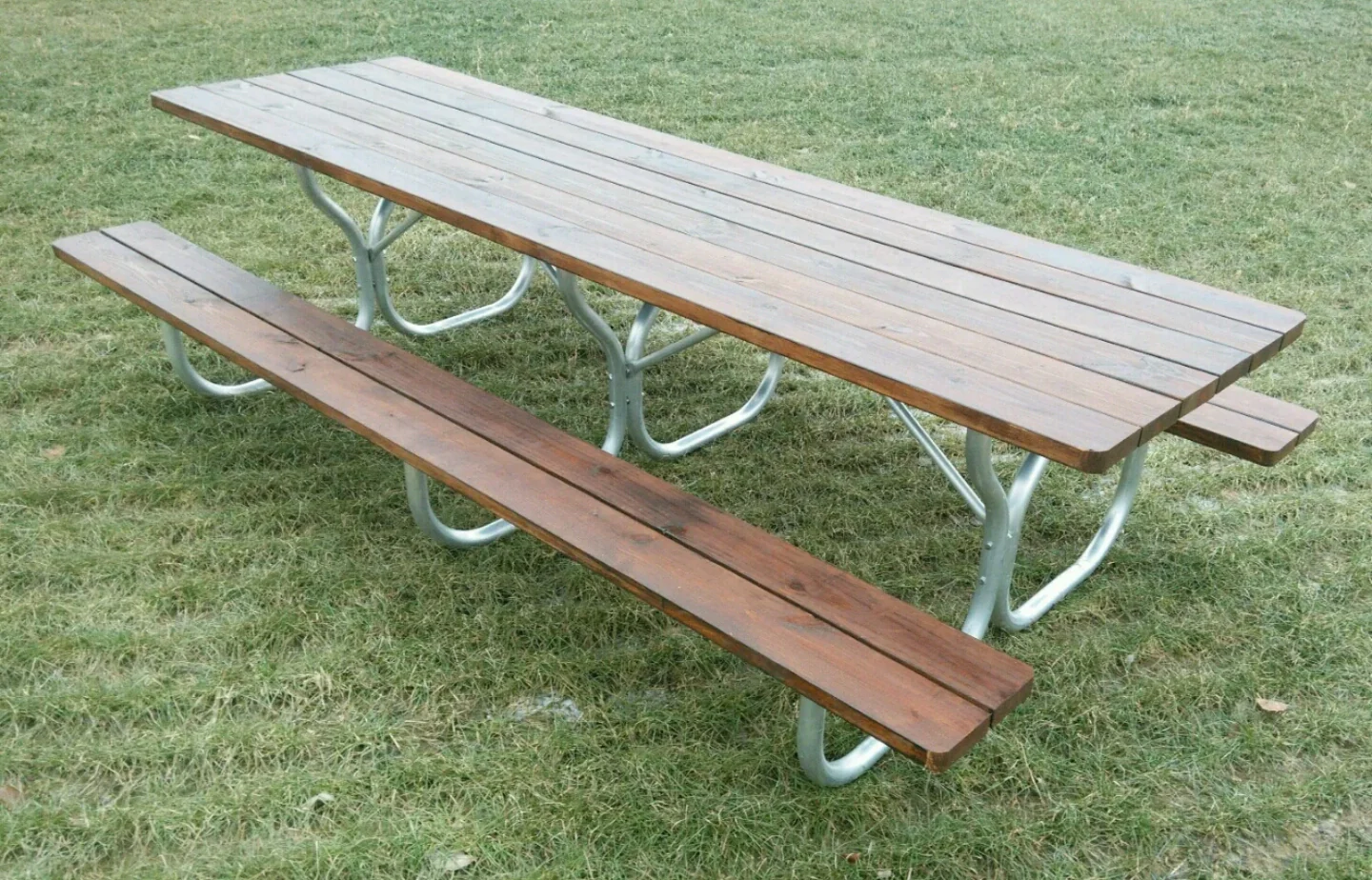 Picnic table with wooden top and bench, on grassy area.