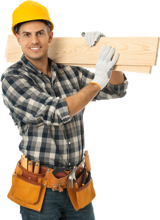 A man wearing a hard hat and gloves is carrying a piece of wood.