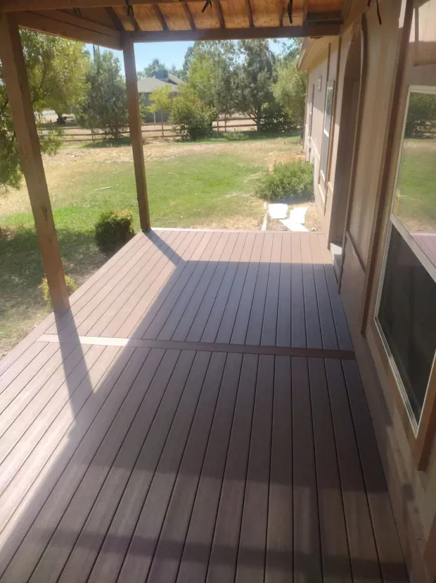 A porch with a covered roof and a view of a grassy field.