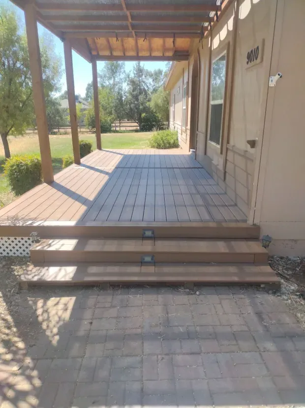 A porch with stairs leading up to it and a pergola over it.