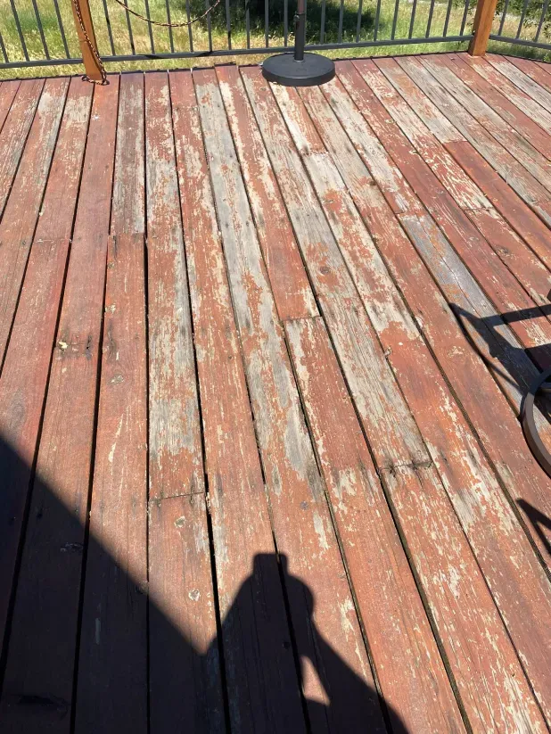A wooden deck with a shadow of a person on it.