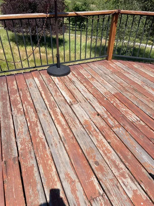 A wooden deck with a metal railing and umbrella stand.