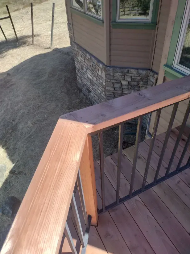 A wooden deck with a metal railing in front of a house