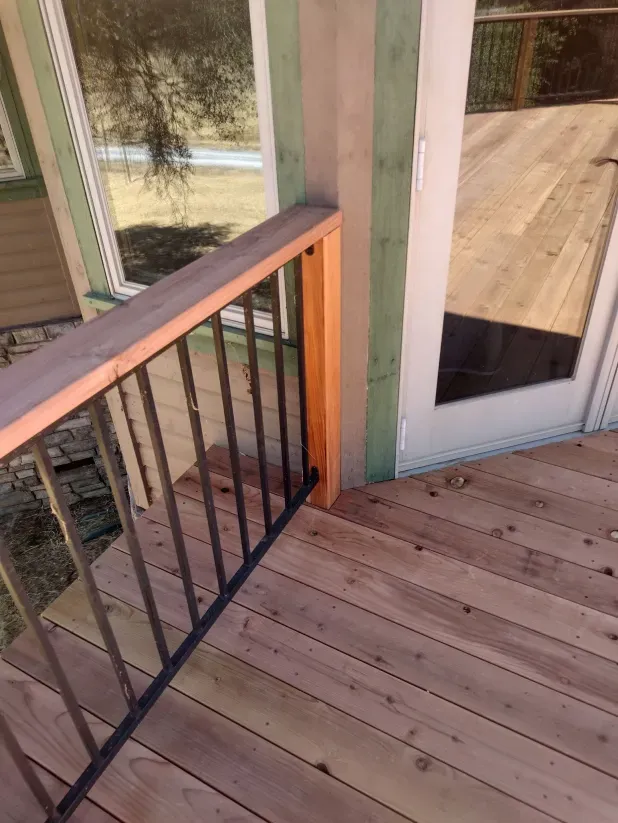 A wooden deck with a metal railing and a sliding glass door