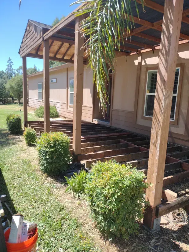 A wooden deck is being built in front of a house.
