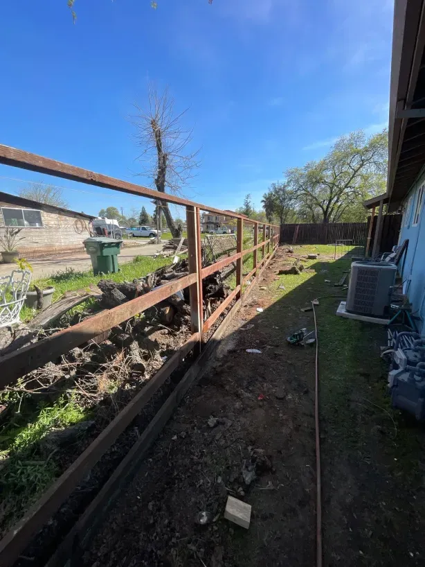 A wooden fence is being built in the backyard of a house.