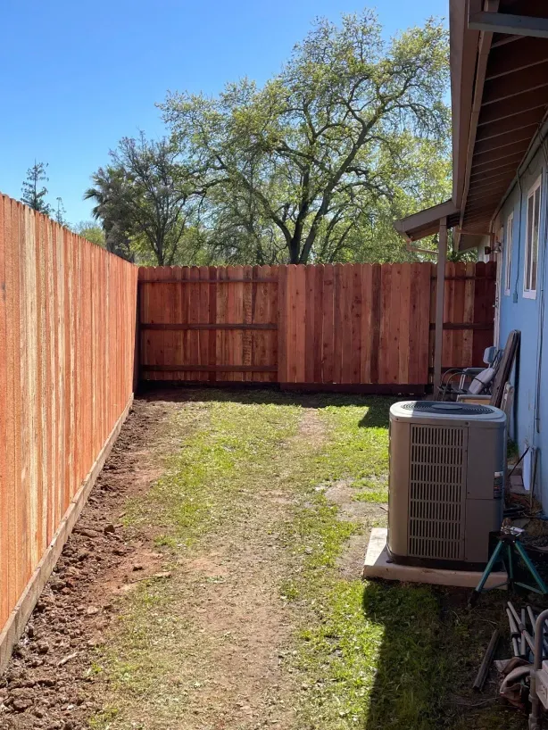 There is a wooden fence in the backyard of a house.