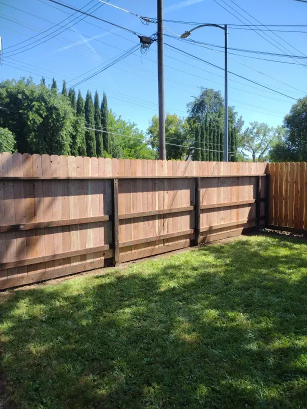 A wooden fence surrounds a lush green yard.
