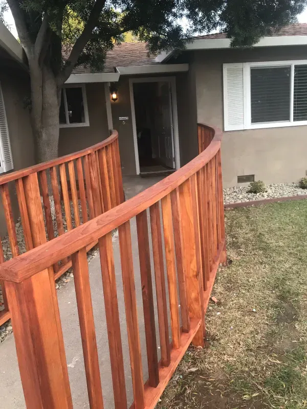 A curved wooden fence leading to a house