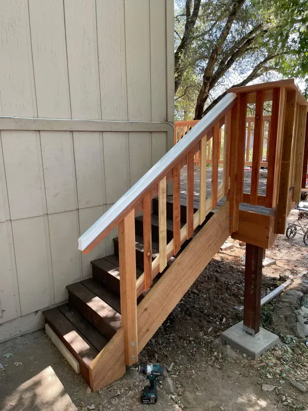 A wooden staircase is being built on the side of a house