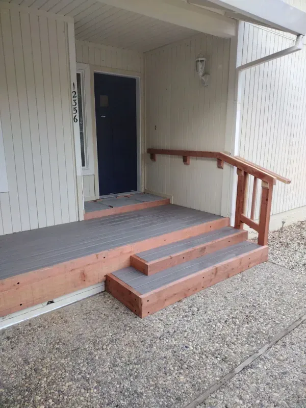 A wooden porch with stairs and a blue door