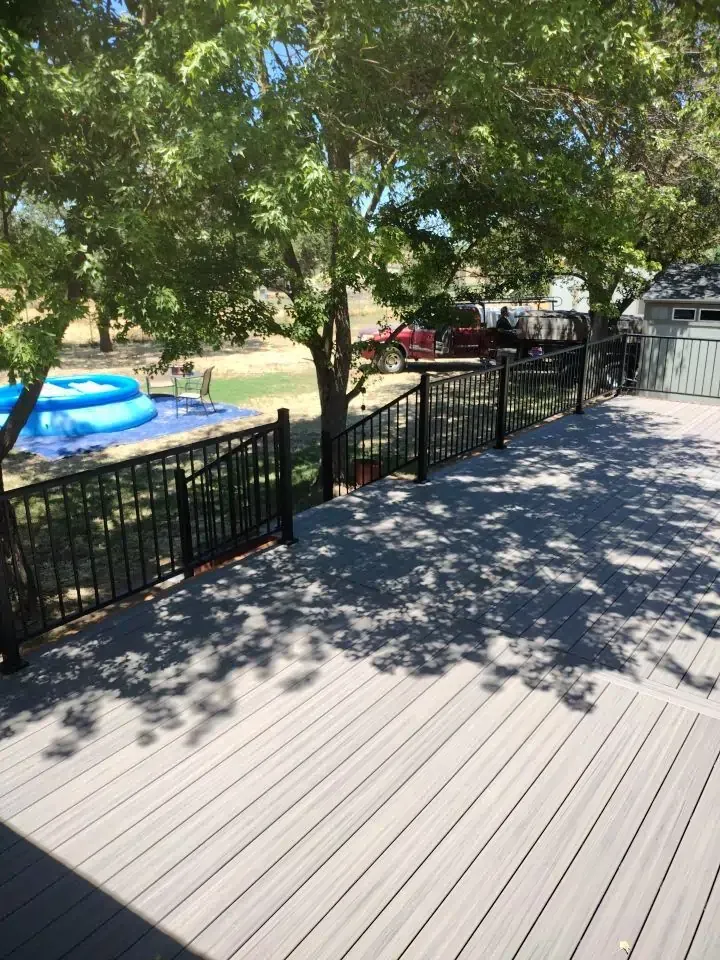 A large deck with a pool in the background