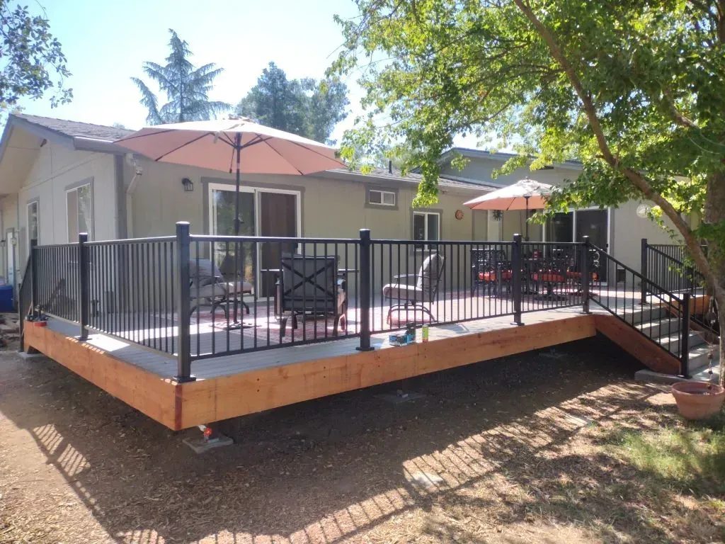 A large deck with umbrellas and chairs in front of a house.