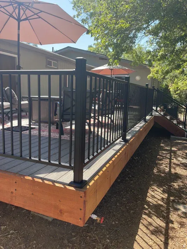 A wooden deck with a metal railing and umbrellas