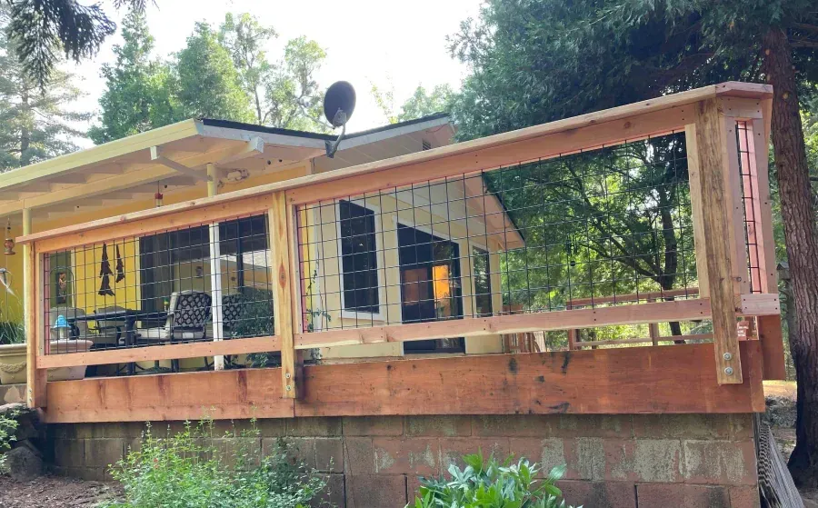 A small house with a wooden porch and a satellite dish on the roof.
