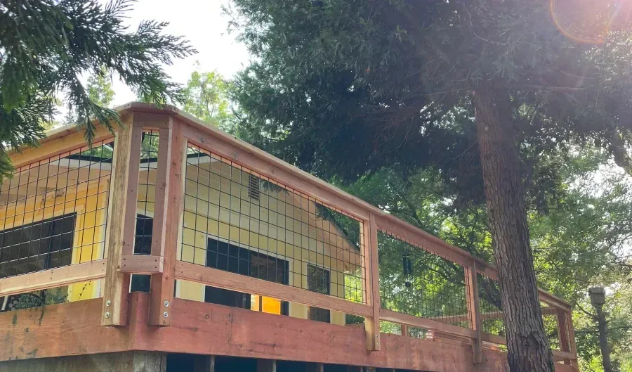 A house under construction with a wooden deck surrounded by trees