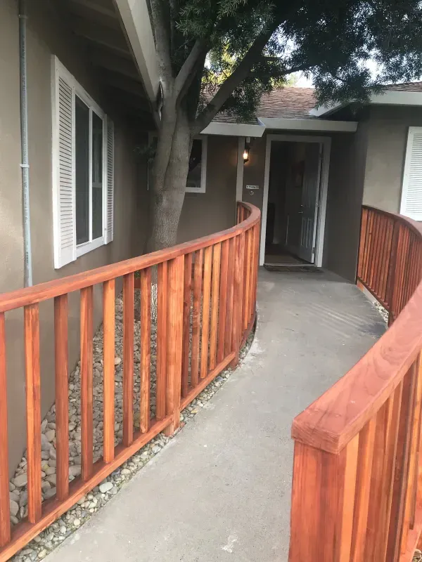 A wooden fence along a walkway leading to a house