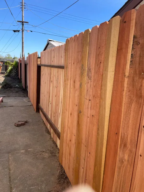 A wooden fence is sitting on the side of a road.
