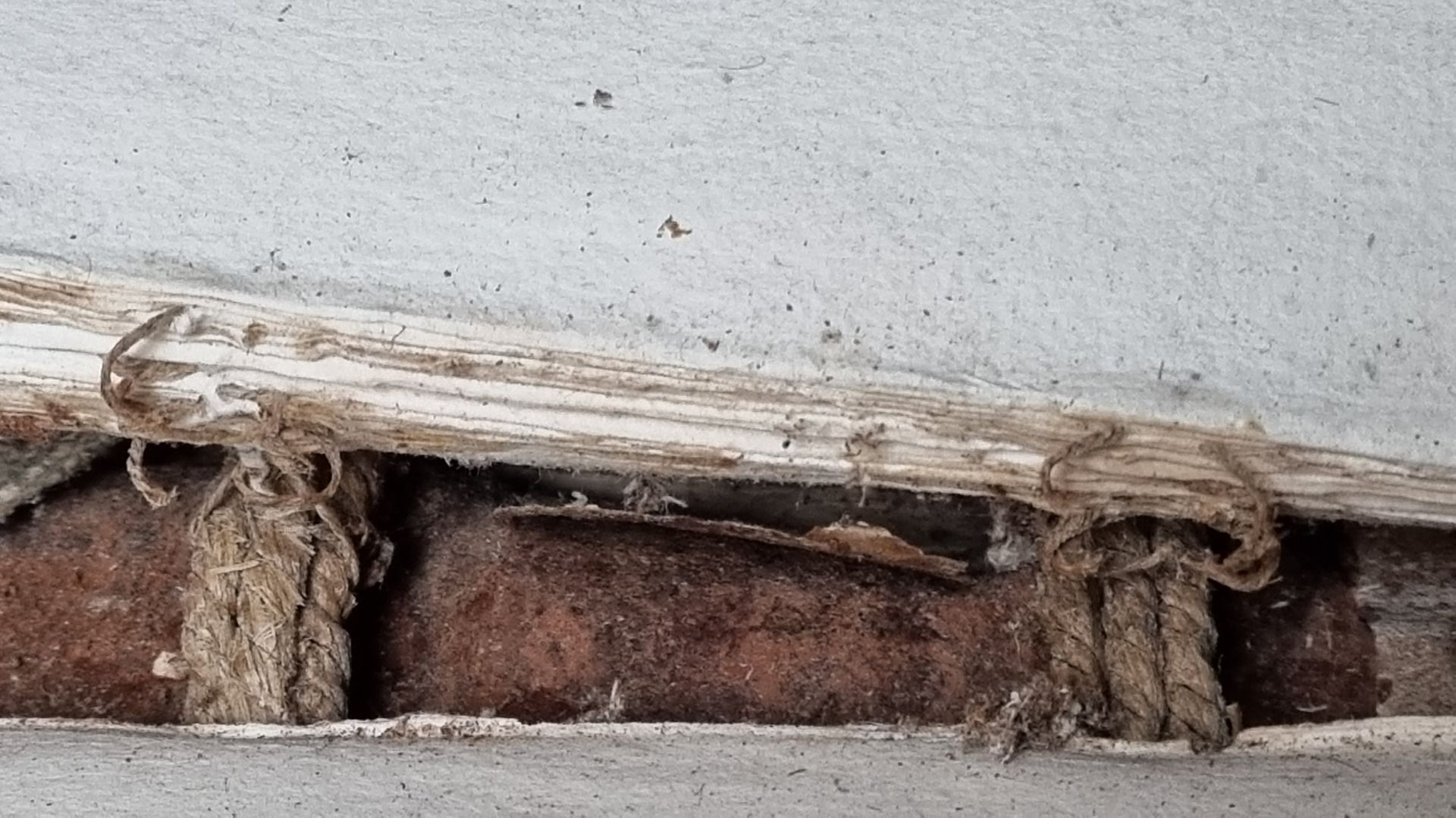 Un gros plan d'un morceau de bois et d'une corde sur un mur.