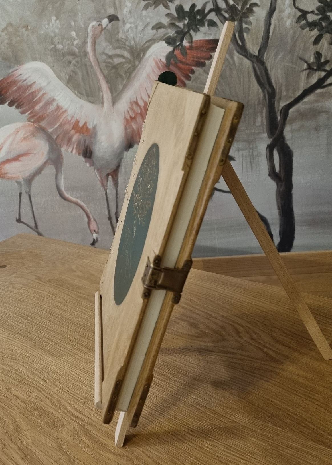 Un livre est posé sur un chevalet en bois avec des flamants roses en arrière-plan.