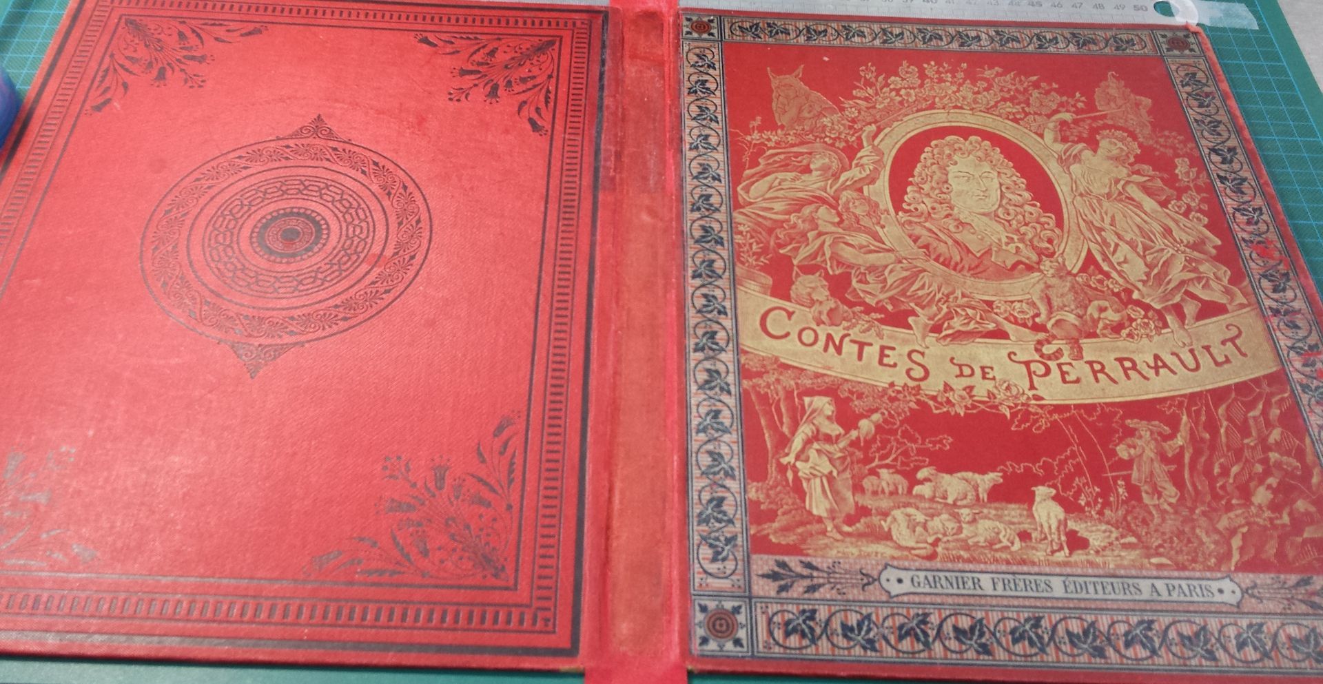 Un livre rouge avec une bordure dorée est posé sur une table.