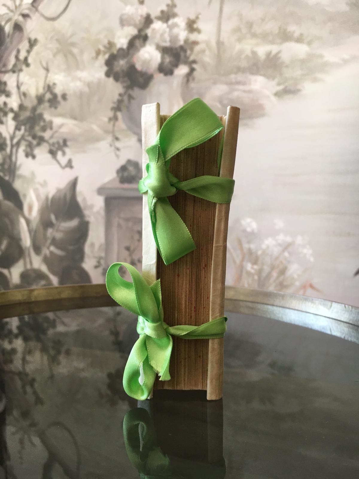 Un livre en bois avec un ruban vert noué autour est posé sur une table.