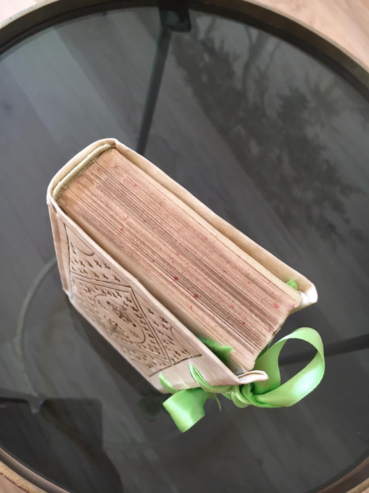 Un livre avec un ruban vert est posé sur une table en verre