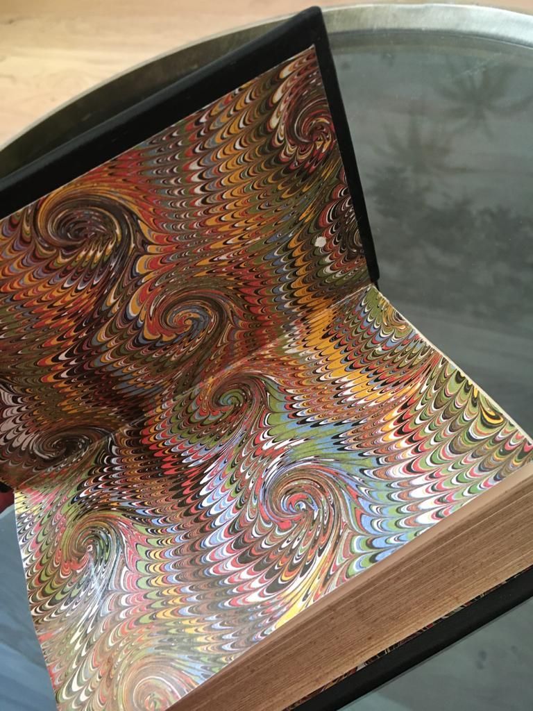 Une personne tient un livre avec une couverture marbrée sur une table.