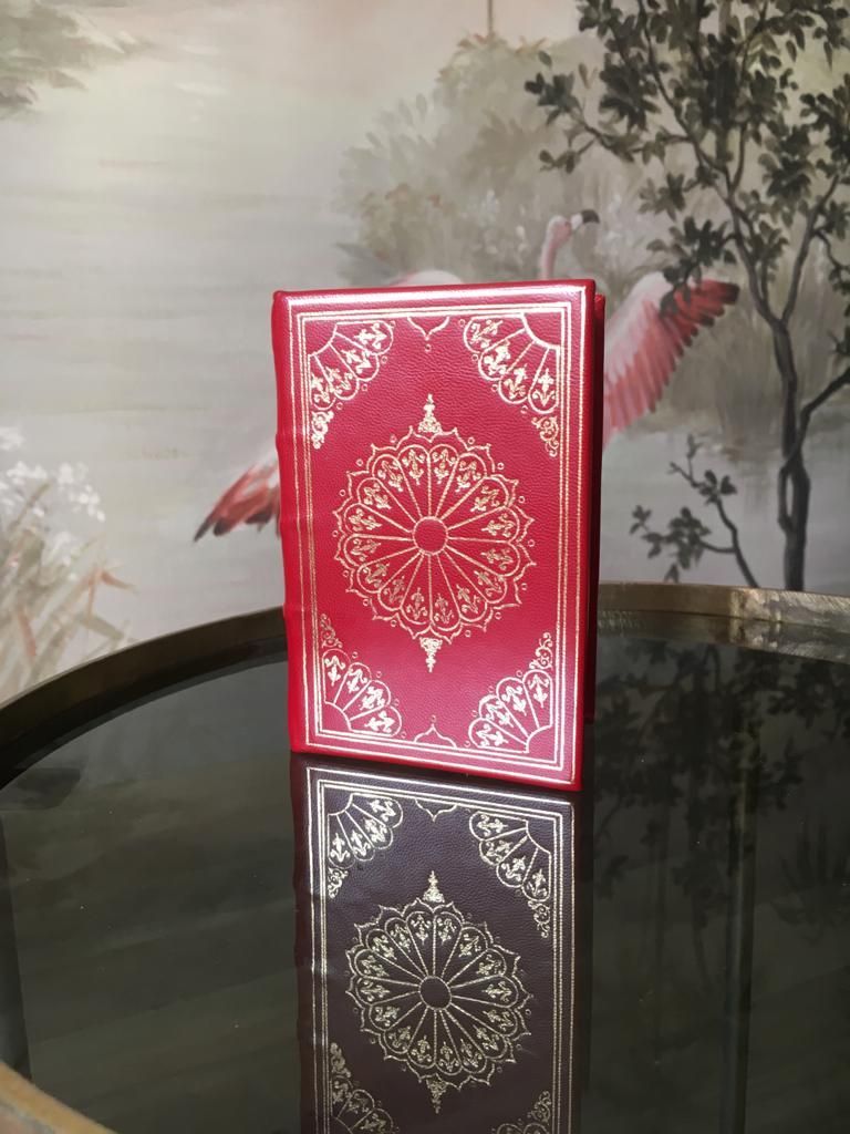 Un livre rouge est posé sur une table en verre.