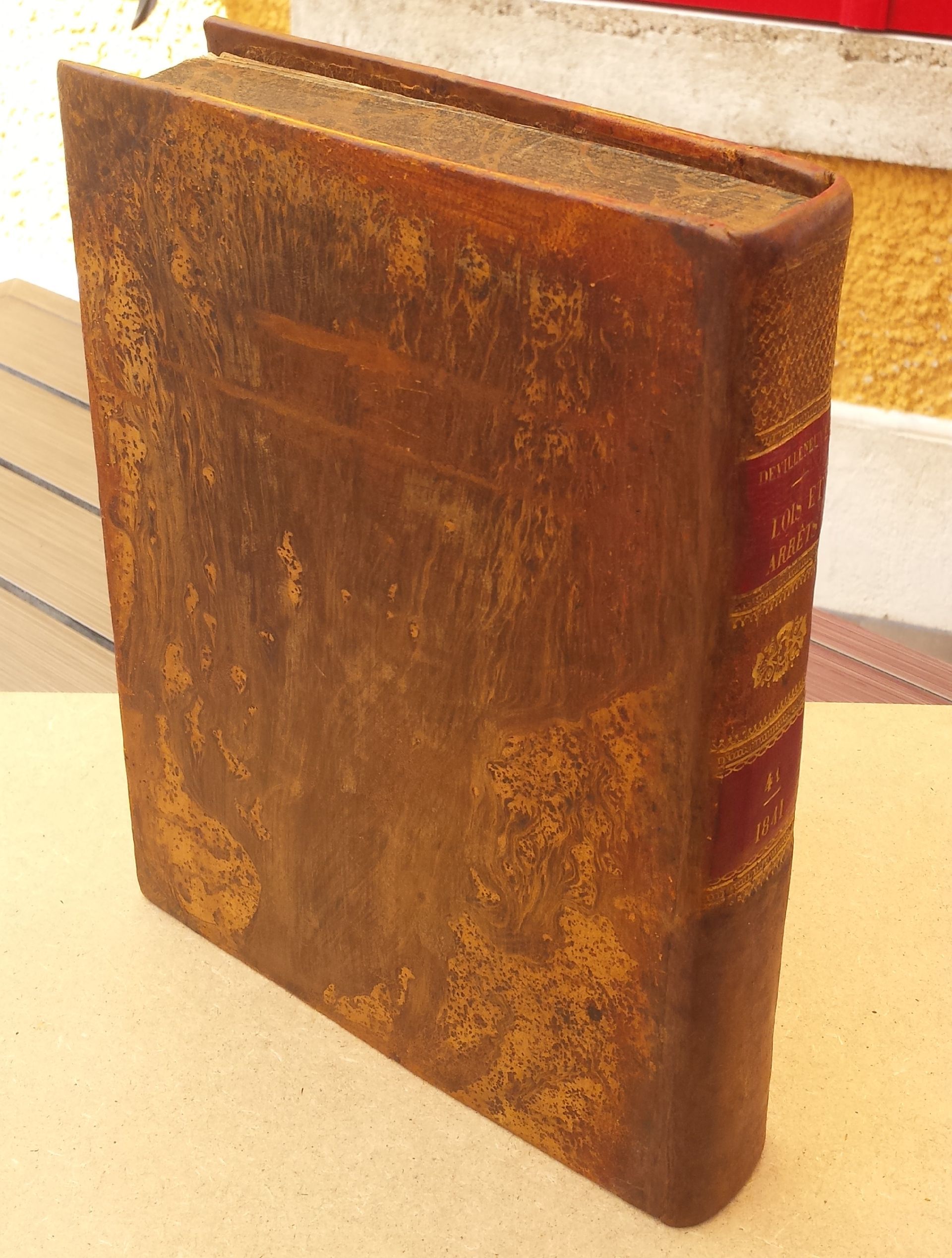 Un livre marron avec une tranche rouge est posé sur une table