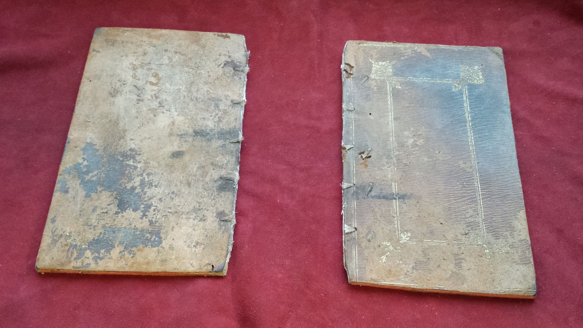 Deux vieux livres sont posés sur un tissu rouge