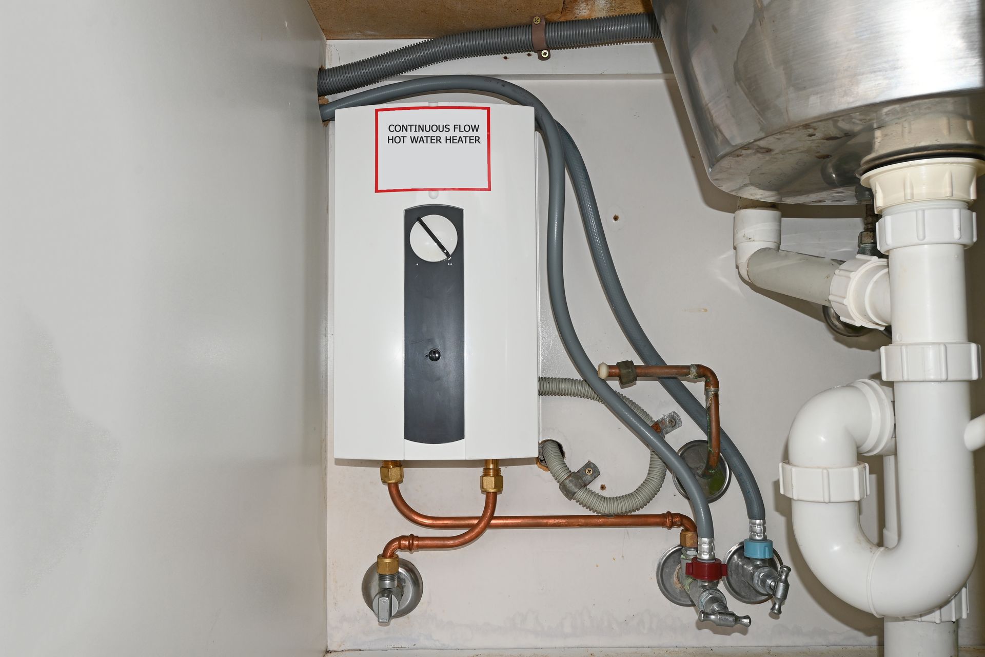 A water heater is installed under a sink in a kitchen