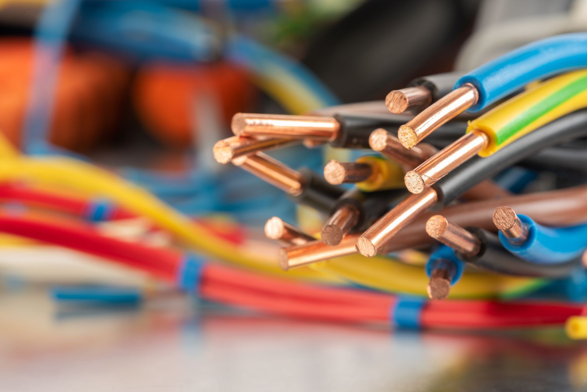 A close-up of several electrical wires with colorful plastic insulation, showing exposed copper ends at the front.