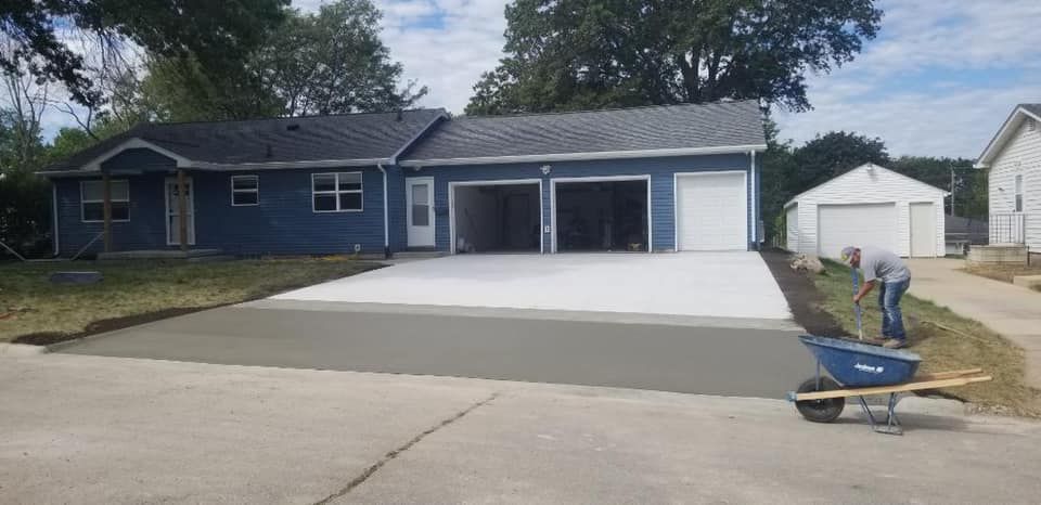 A man is working on a concrete driveway in front of a house.
