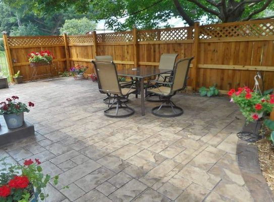 A patio with a table and chairs and a wooden fence
