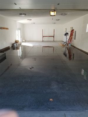 A large empty garage with a black floor and white walls.