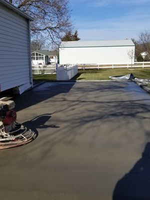 A concrete driveway is being built in front of a mobile home.