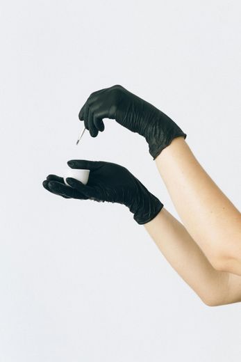 A person wearing black gloves is holding a pipette in their hand.
