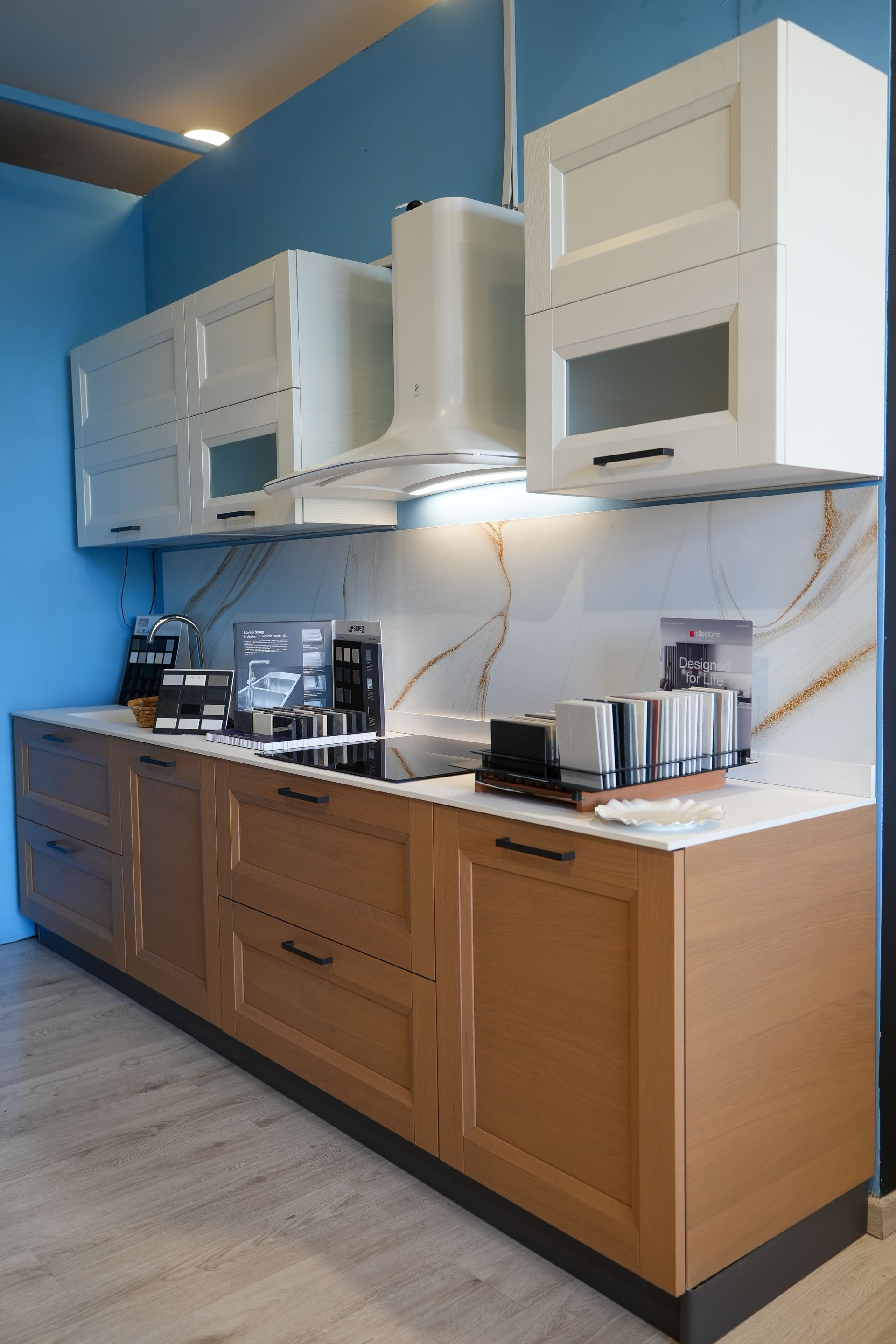 Una cucina con mobili in legno e mobili bianchi e un forno con fornelli.