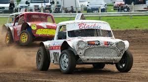 Two race cars are racing on a dirt track.
