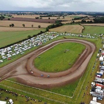 An aerial view of a race track surrounded by fields and tents.
