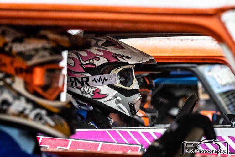 A person wearing a helmet and goggles is sitting in a car.