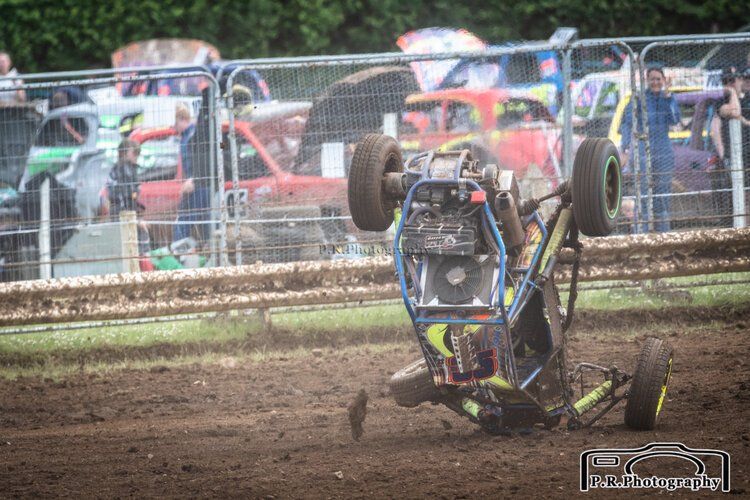 A person is riding a buggy on a dirt track.
