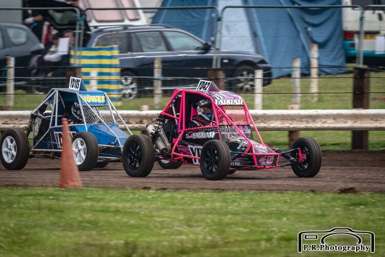 Three go karts are racing on a dirt track.