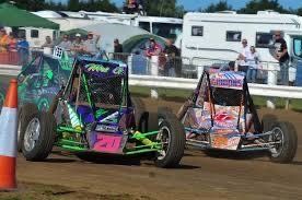 Two go karts are racing on a dirt track.