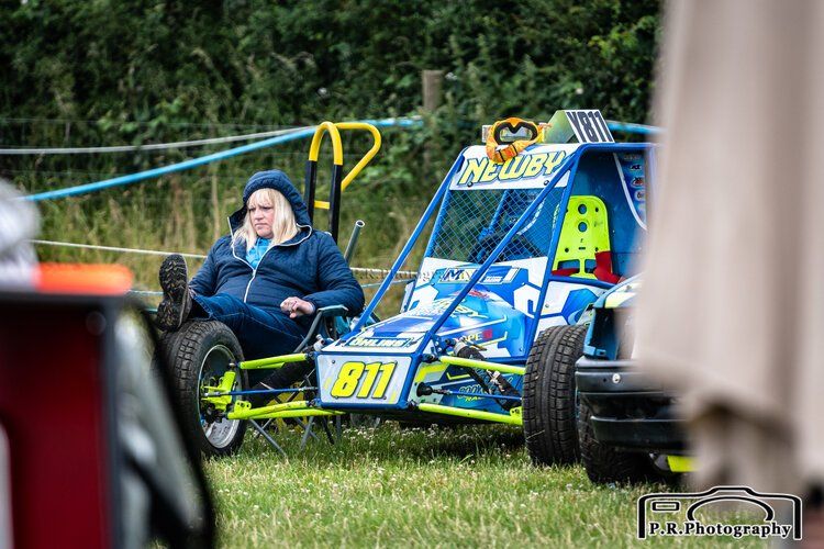 A woman is sitting in a buggy in a field.