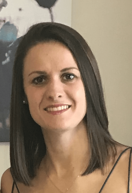 A woman with long dark hair is smiling for the camera.