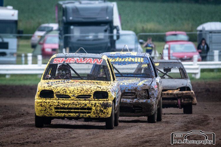 A group of cars are racing on a dirt track.