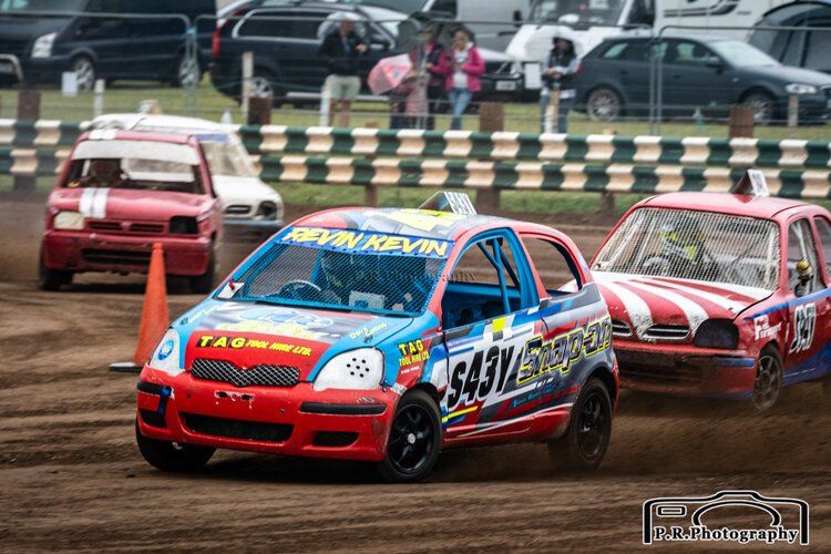A group of cars are racing on a dirt track.